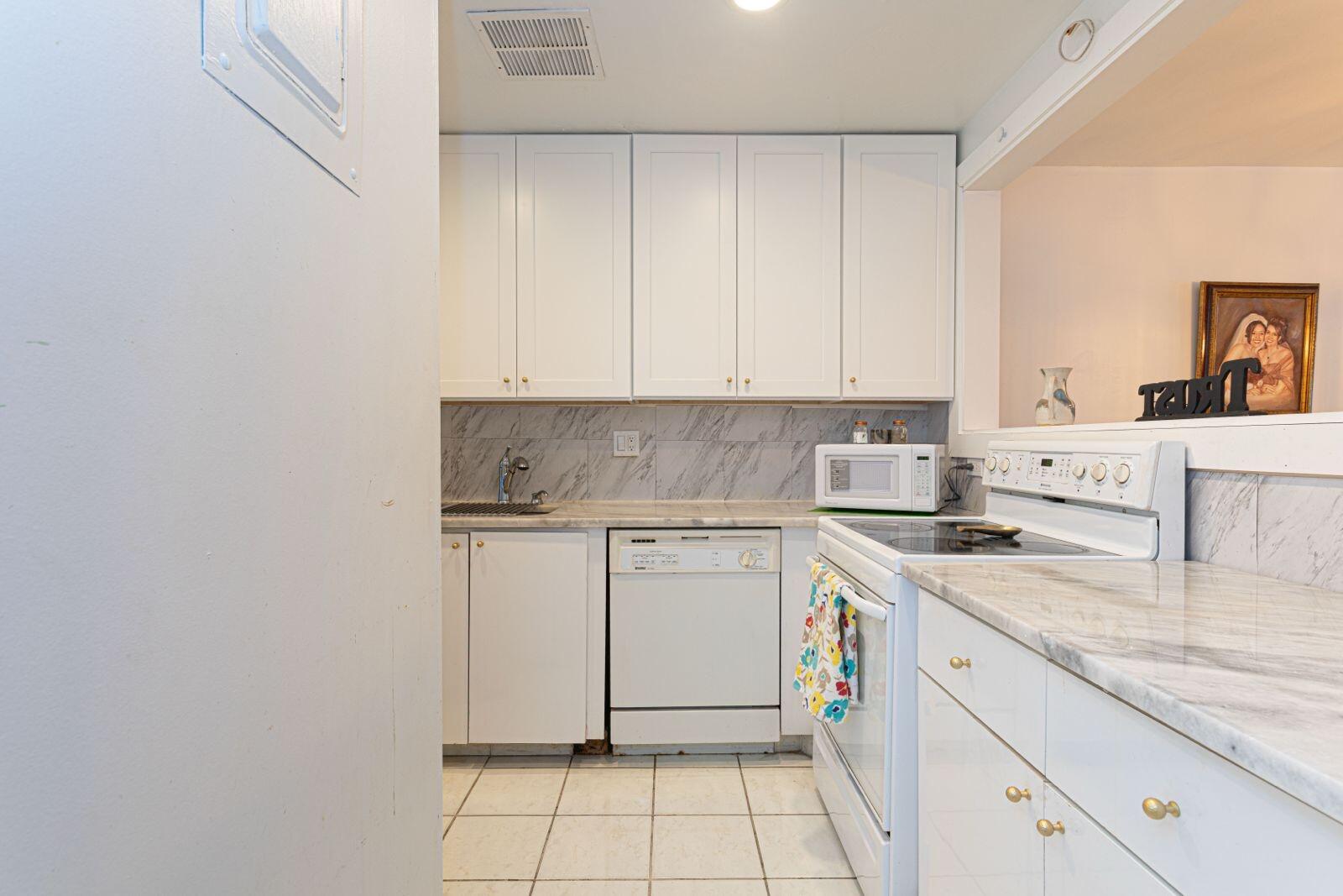 1421 Northwest 19th Terrace, Unit 102 Delray Beach, FL 33445 - Photo 8 of 31 a kitchen with stainless steel appliances granite countertop a sink stove and white cabinets