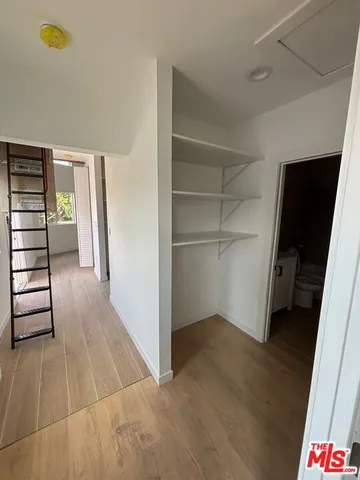 a view of an empty room with wooden floor and closet