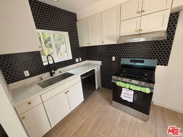 a kitchen with granite countertop a stove a sink and a microwave