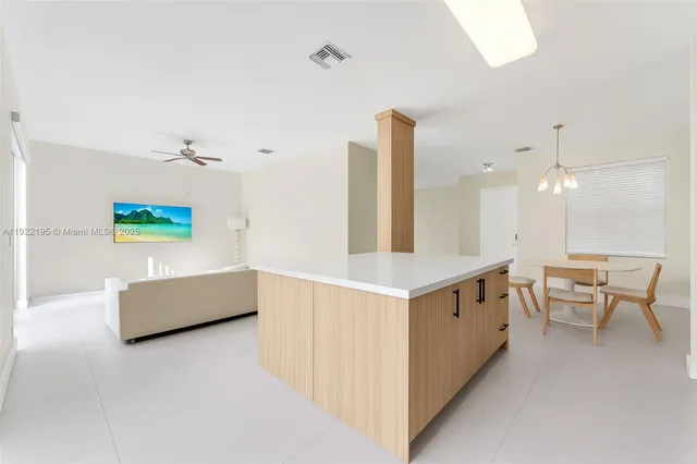 an open kitchen with granite countertop white cabinets and couches