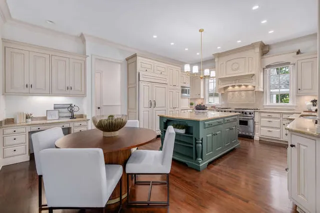 a kitchen with stainless steel appliances kitchen island granite countertop a table chairs and a refrigerator