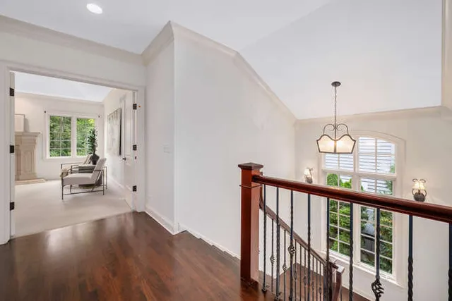a view of a hallway with wooden floor and chandelier
