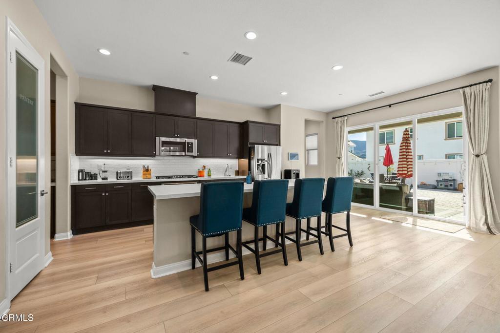 390 Rose Street Fillmore, CA 93015 - Photo 8 of 58 a kitchen with stainless steel appliances kitchen island granite countertop a refrigerator a stove a sink a dining table and chairs with wooden floor