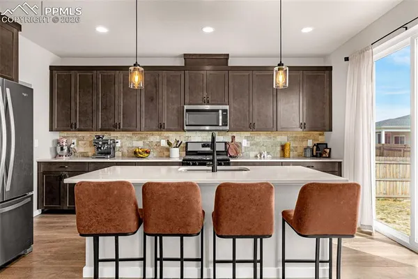 a kitchen with granite countertop a table chairs microwave and cabinets