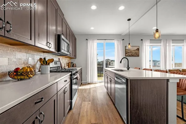 a kitchen with stainless steel appliances a sink a stove and a wooden floors