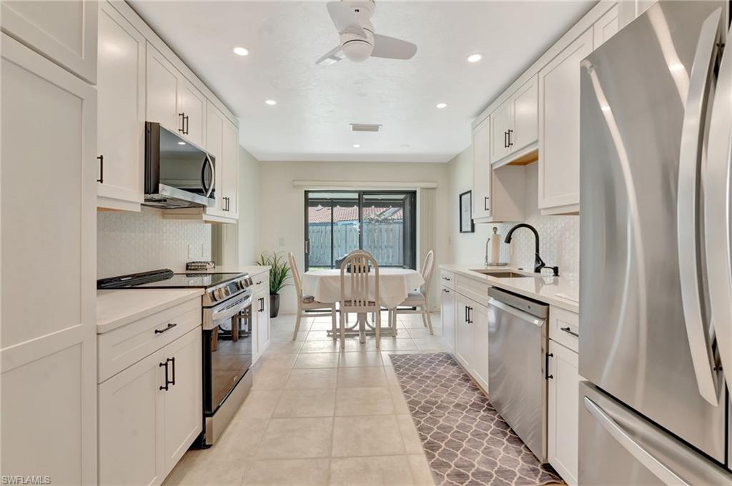 731 Reef Point Circle Naples, FL 34108 - Photo 12 of 47 a large kitchen with stainless steel appliances granite countertop a stove and a sink
