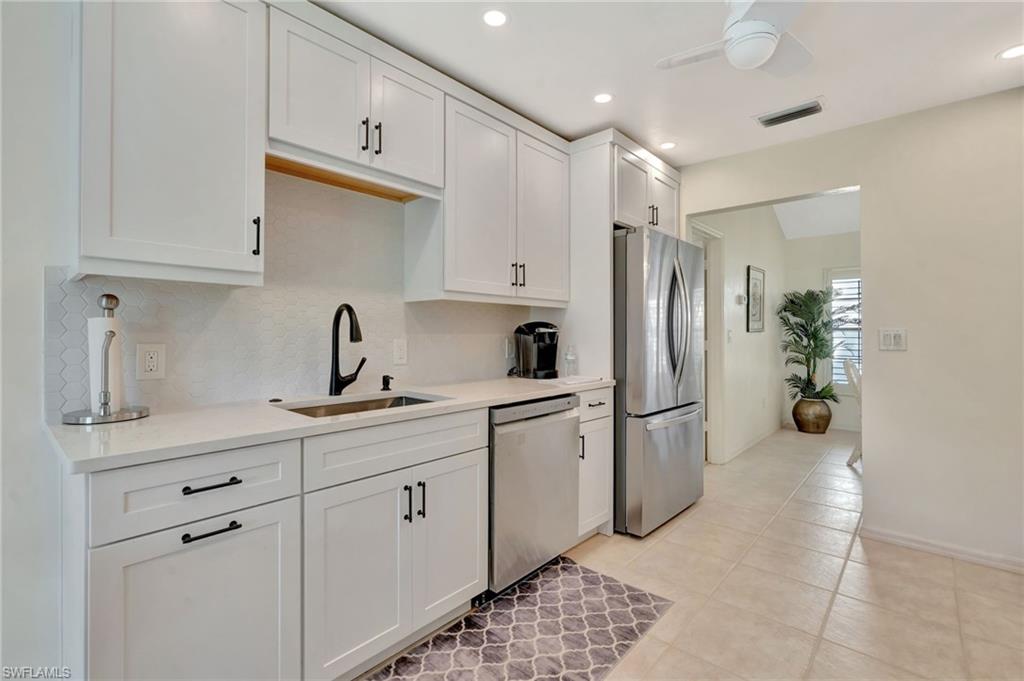 731 Reef Point Circle Naples, FL 34108 - Photo 13 of 47 a kitchen with stainless steel appliances a refrigerator sink and cabinets