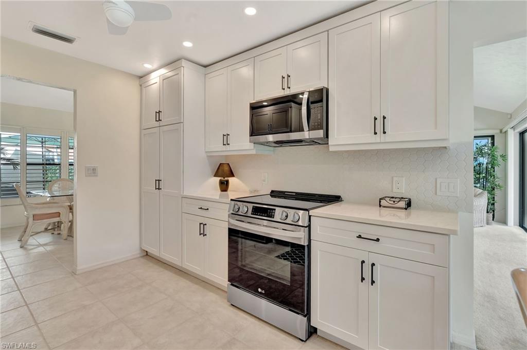 731 Reef Point Circle Naples, FL 34108 - Photo 14 of 47 a kitchen with white cabinets and stainless steel appliances