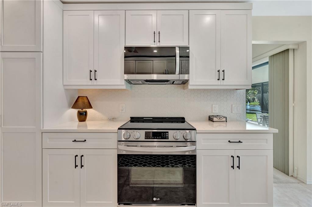 731 Reef Point Circle Naples, FL 34108 - Photo 16 of 47 a kitchen with stainless steel appliances granite countertop a stove a microwave and cabinets