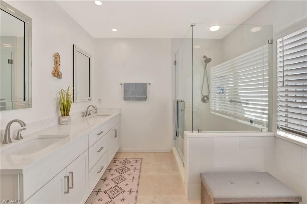 731 Reef Point Circle Naples, FL 34108 - Photo 23 of 47 a bathroom with a double vanity sink a mirror and a bathtub