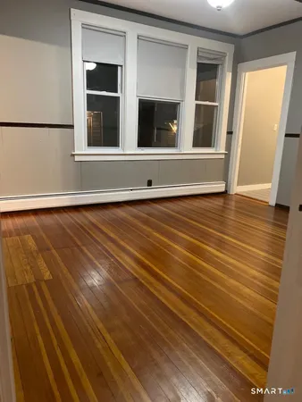 a view of an empty room with wooden floor and a window
