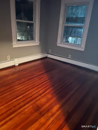 a view of an empty room with wooden floor and a window