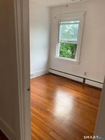 a view of a room with wooden floor a ceiling fan and window