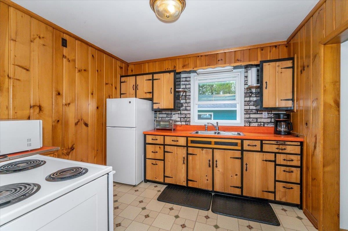 5253 Midway Road Duluth, MN 55811 - Photo 6 of 28 Kitchen featuring a sink, white appliances, wood walls, brown cabinets, and ornamental molding