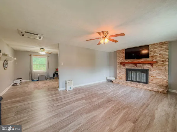 a view of a livingroom with a fireplace wooden floor and a chandelier fan