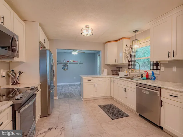 a kitchen with stainless steel appliances white cabinets and a stove top oven