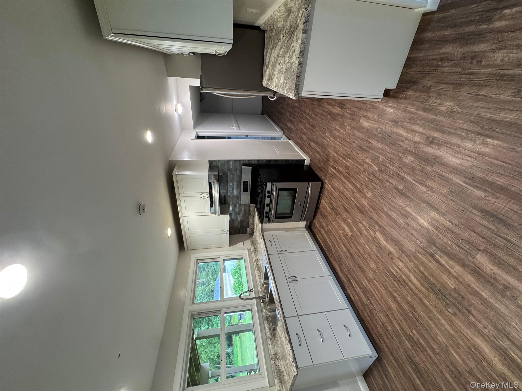 1145 Glen Road, Unit B Shrub Oak, NY 10588 - Photo 2 of 13 Kitchen with white cabinetry, stainless steel range with gas cooktop, light stone counters, backsplash, and dark wood-style flooring