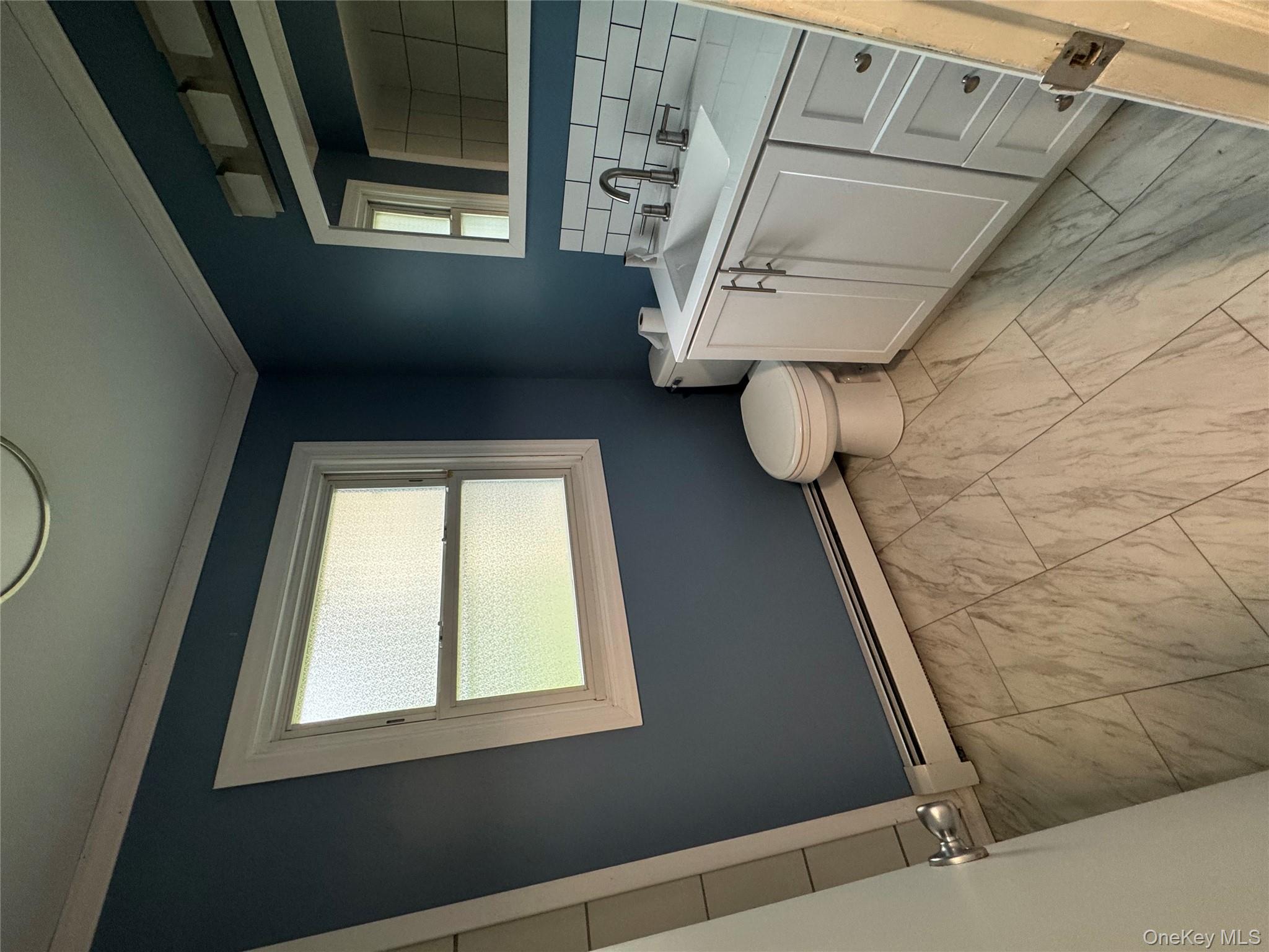 1145 Glen Road, Unit B Shrub Oak, NY 10588 - Photo 5 of 13 Half bath with vanity, a baseboard radiator, decorative backsplash, crown molding, and light marble finish flooring