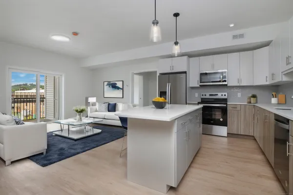a large kitchen with stainless steel appliances kitchen island granite countertop a sink dishwasher a stove a dining table and chairs with wooden floor