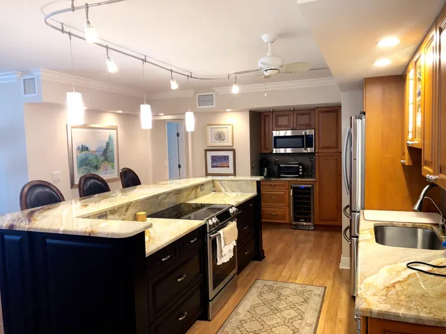 a large kitchen with kitchen island a large counter top and stainless steel appliances