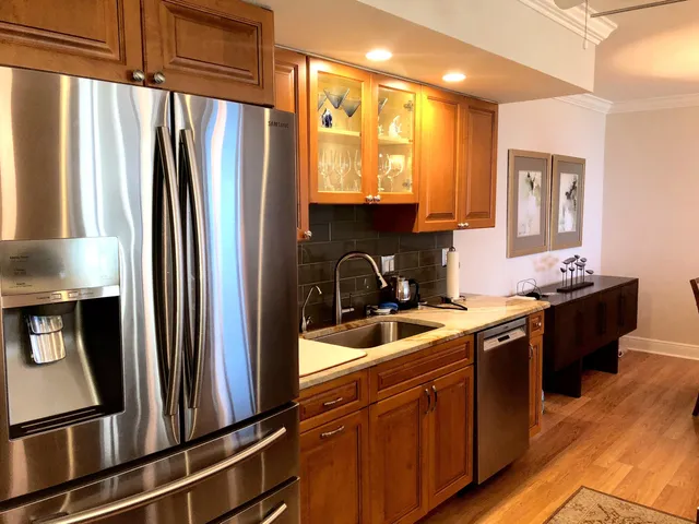 a kitchen with stainless steel appliances granite countertop a refrigerator a sink dishwasher a stove and a refrigerator