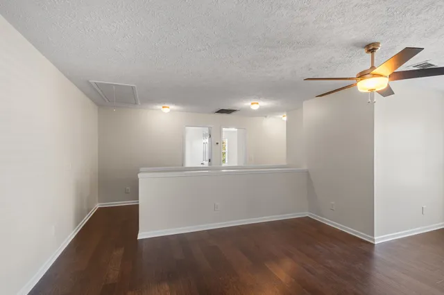 an empty room with wooden floor and ceiling fan