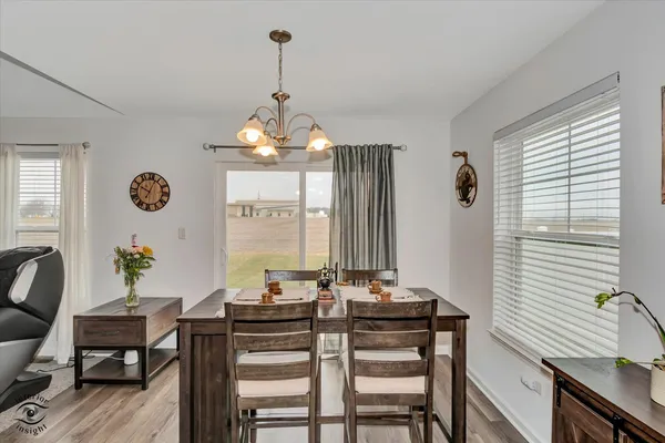 a view of a dining room and livingroom with furniture wooden floor a chandelier