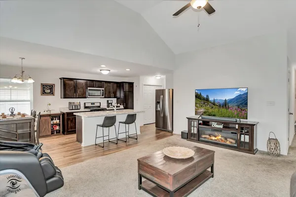 a living room with stainless steel appliances furniture and a kitchen view