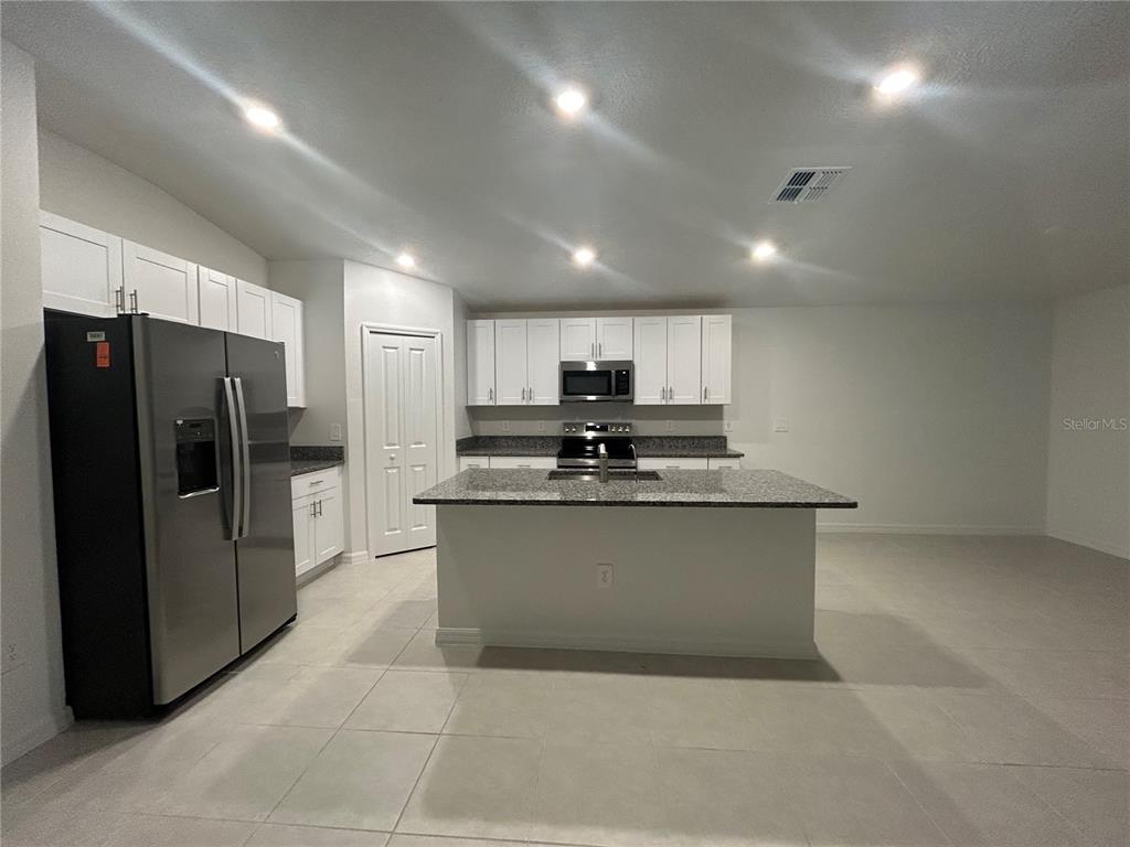 13095 Calcite Blue Avenue Wimauma, FL 33598 - Photo 11 of 28 a kitchen with stainless steel appliances a refrigerator sink and microwave