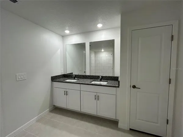 a bathroom with a granite countertop sink a mirror and shower