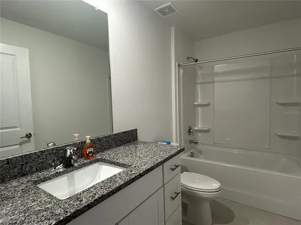 a bathroom with a granite countertop sink and a mirror