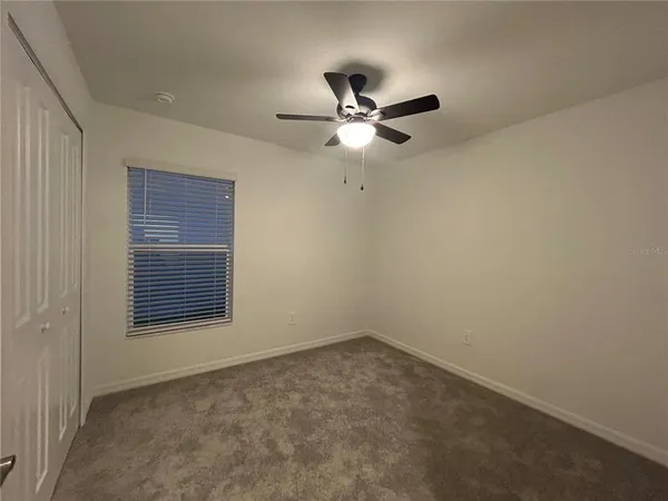 an empty room with closet and ceiling fan