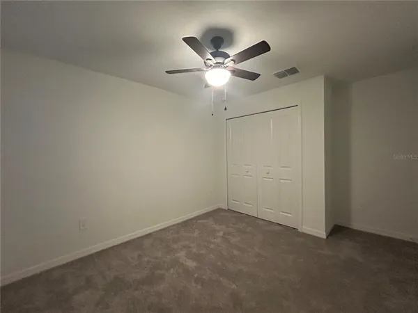 an empty room with closet and ceiling fan