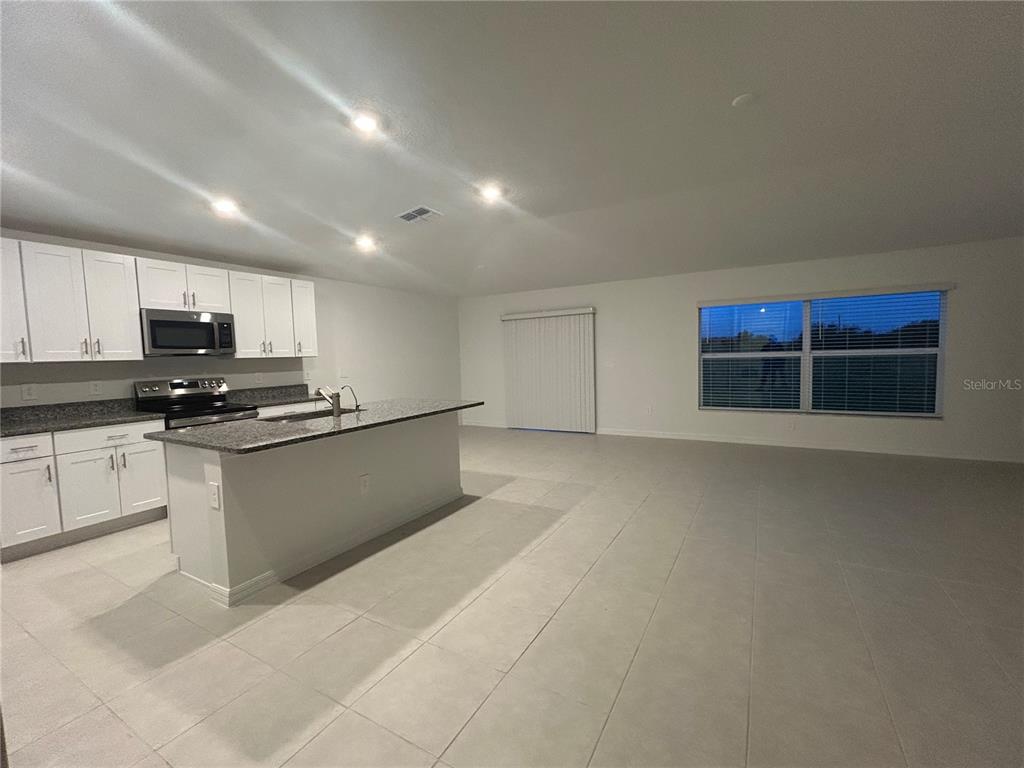 13095 Calcite Blue Avenue Wimauma, FL 33598 - Photo 5 of 28 a kitchen with stainless steel appliances granite countertop a stove a sink and a refrigerator