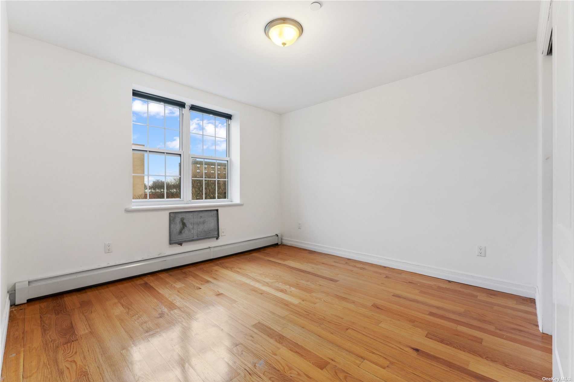 53-12 102nd Street Queens, NY 11368 - Photo 5 of 20 an empty room with wooden floor and windows