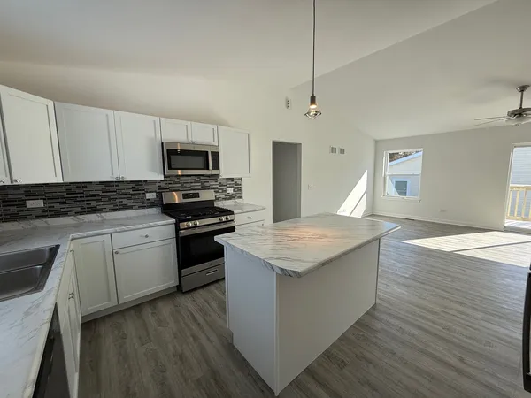 a kitchen with granite countertop a stove top oven a sink dishwasher and a refrigerator with wooden floor