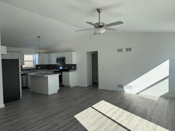 a kitchen with stainless steel appliances kitchen island a refrigerator sink and cabinets