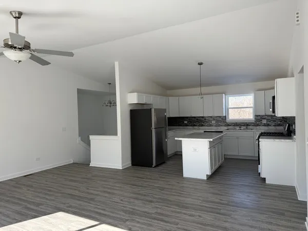 a kitchen with a refrigerator and white cabinets