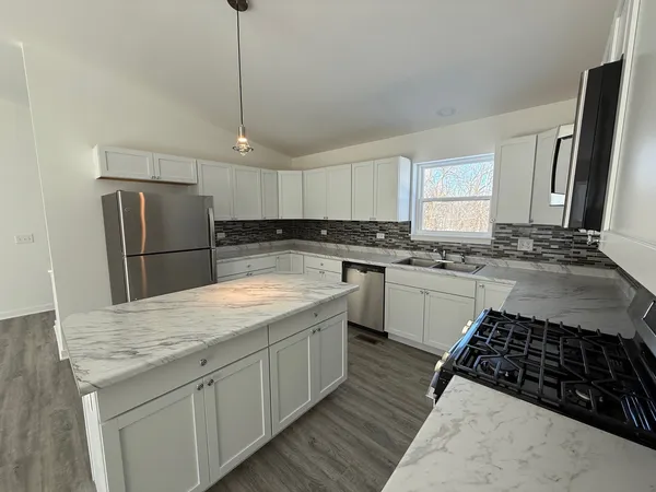 a kitchen with stainless steel appliances granite countertop a sink stove a refrigerator and cabinets