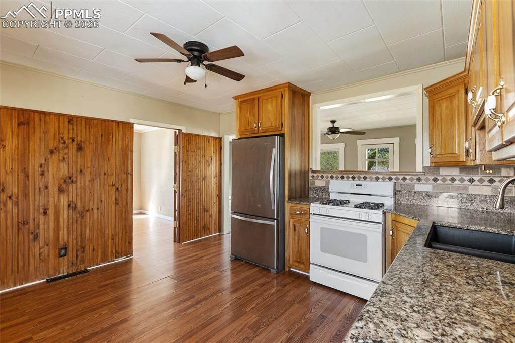 10355 Link Road Fountain, CO 80817 - Photo 14 of 45 a kitchen with stainless steel appliances granite countertop a refrigerator a stove and a sink with wooden floor