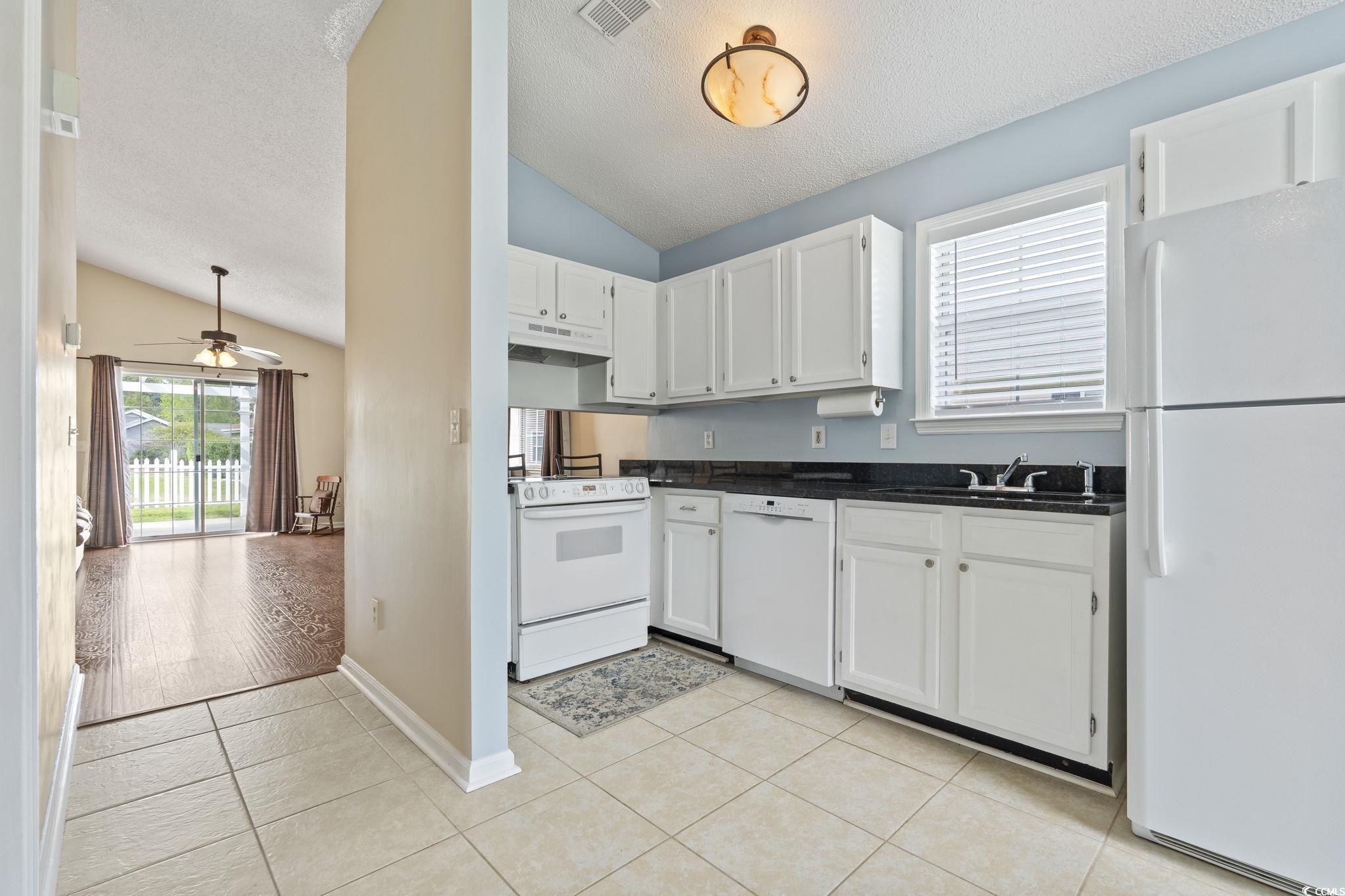 1130 Ganton Way Myrtle Beach, SC 29588 - Photo 5 of 30 Kitchen featuring white appliances, light tile patterned flooring, dark countertops, under cabinet range hood, and visible vents