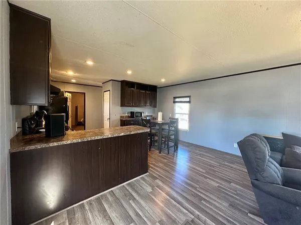 a kitchen with stainless steel appliances granite countertop a refrigerator a stove top oven a sink dishwasher a dining table and chairs with wooden floor