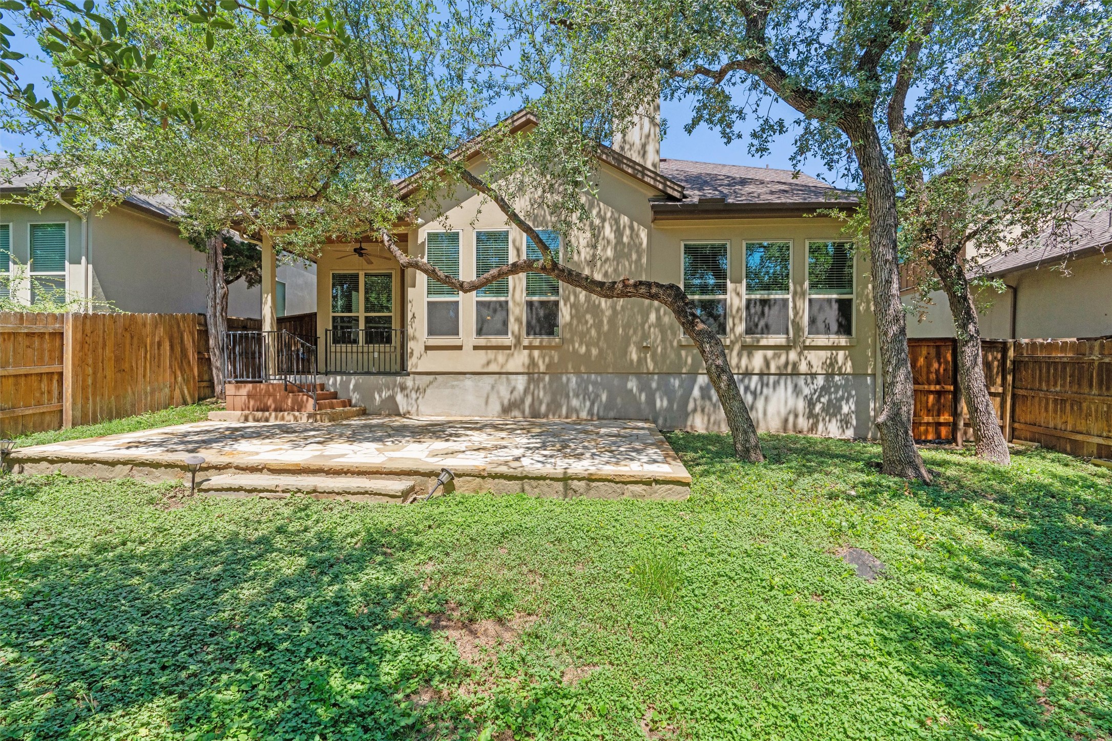 8417 Etienne Cove Austin, TX 78759 - Photo 32 of 35 A private backyard oasis features a stone patio and lush green ground cover, perfect for outdoor enjoyment.