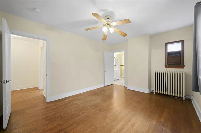 an empty room with wooden floor fan and windows