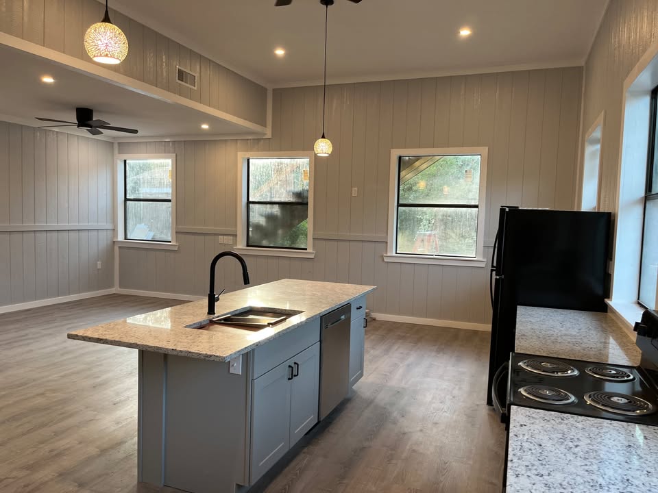 3505 Lone Man Mountain Road, Unit A Wimberley, TX 78676 - Photo 1 of 11 A well-lit, open-concept kitchen and living area featuring a central island with a sink.
