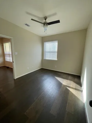 an empty room with a ceiling fan and windows