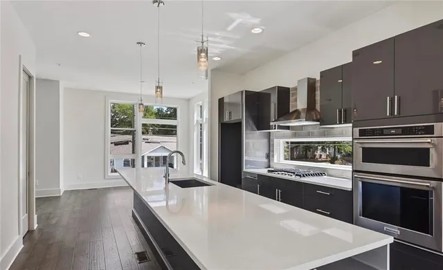 a kitchen with stainless steel appliances kitchen island granite countertop a stove top oven a sink dishwasher a dining table and chairs with wooden floor