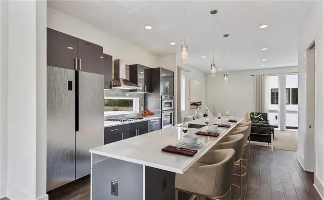 a kitchen with stainless steel appliances kitchen island granite countertop a refrigerator a sink a stove and white cabinets with wooden floor