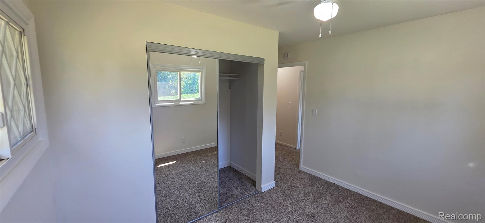 4363 West Dodge Road Clio, MI 48420 - Photo 29 of 52 Bedroom featuring neutral carpeting, a mirrored closet, a ceiling-mounted light fixture, and two windows