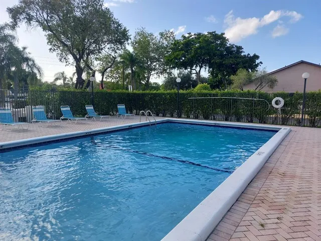 a view of a swimming pool with a patio and trees